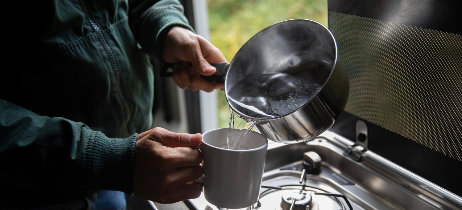 Кастрюля с прозрачной, только что вскипяченной водой, из которой поднимается легкий пар.